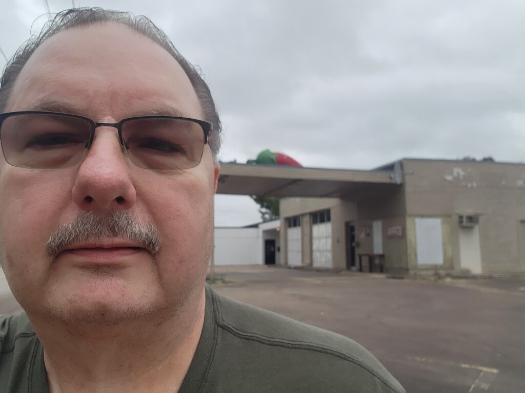 A man with glasses standing in front of an empty building.