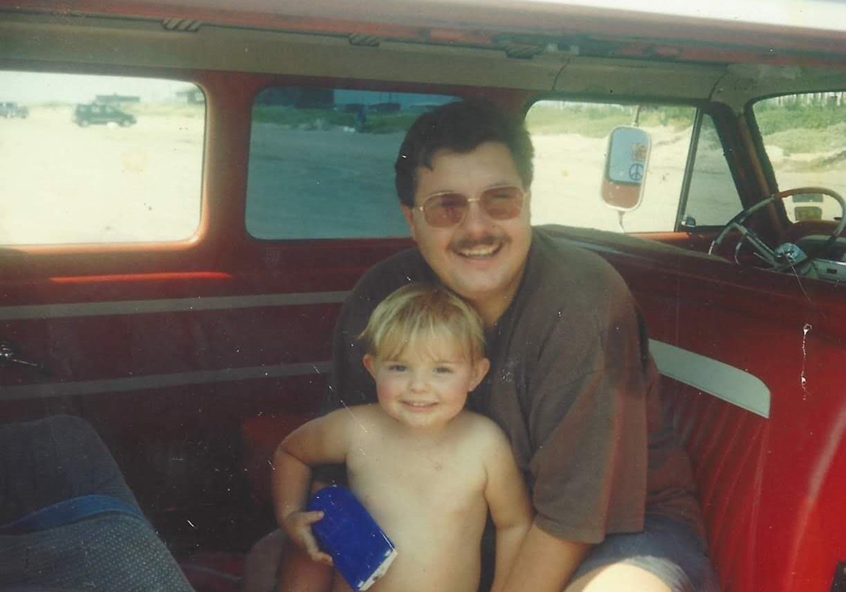 A man and boy in the back of an old van.