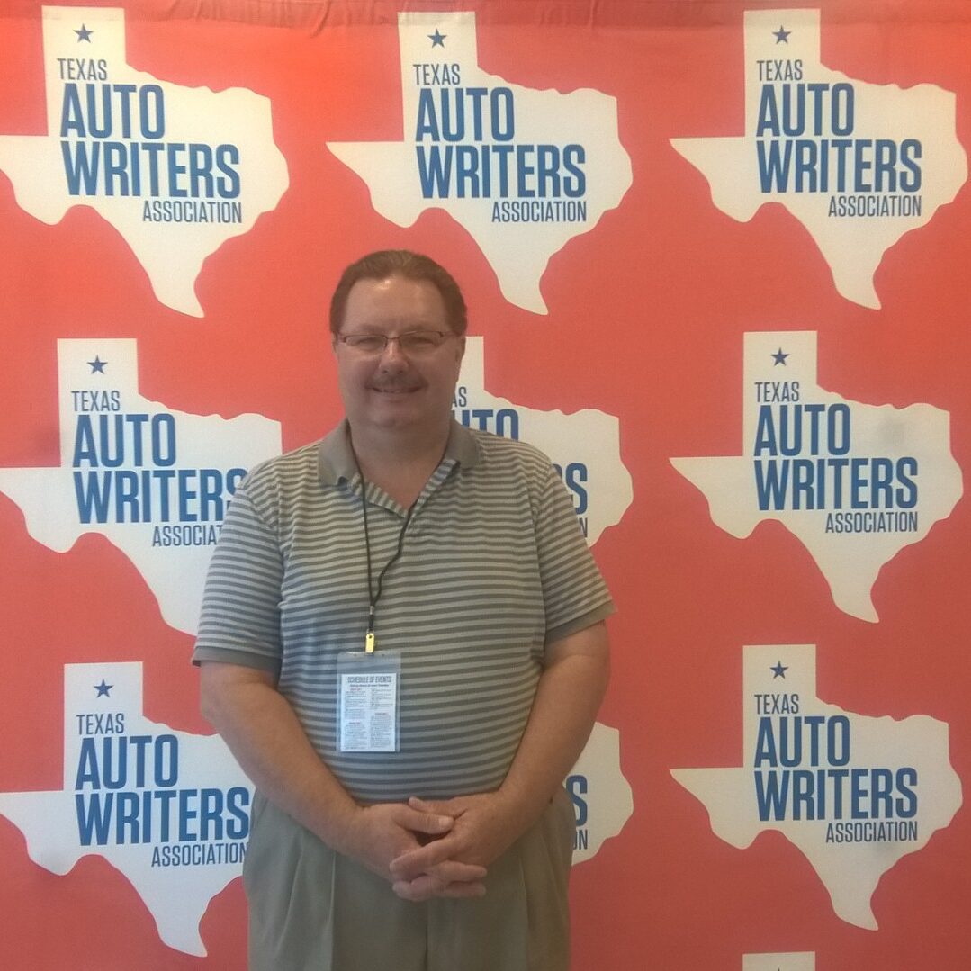 A man standing in front of a wall with texas on it.